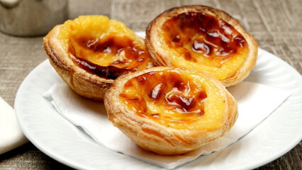 Fototapeta premium Three Freshly Baked Portuguese Custard Tarts Served on a White Plate