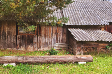 Naklejka premium Old wooden barn with log bench standing in grass
