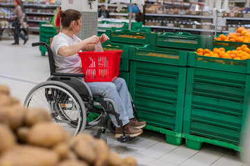 Obraz premium A Caucasian woman in a wheelchair buys fruit at a supermarket.