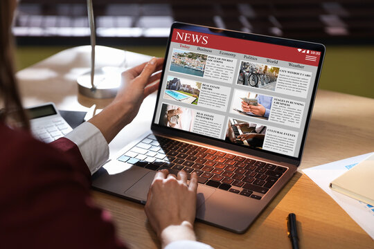 Woman reading online newspaper on laptop at table, closeup