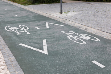 Obraz premium Urban bicycle lane with painted bike symbols and directional arrows on asphalt pavement. Dedicated cycling infrastructure in a modern city promoting sustainable transport, eco-friendly mobility