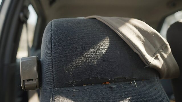 Closeup of a worn and torn car seat with a beige cloth on it