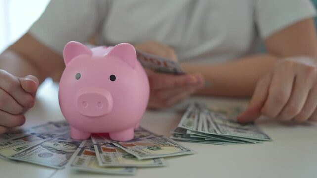 Piggybank used for financial education of girl. Child counts dollars to learn saving responsibility. Finance skills built early. Saving habit formed with help of piggybank during child learning.