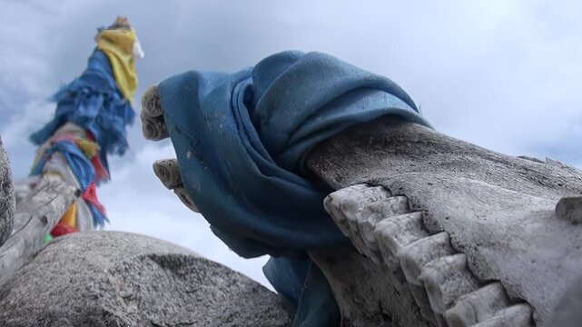Experience tranquil magic of Lake Khuvsgul, Mongolia. Ancient bone, draped in blue cloth, symbolizes timeless devotion next to cascade of vibrant prayer flags. Serene, sacred moment under soft sky.