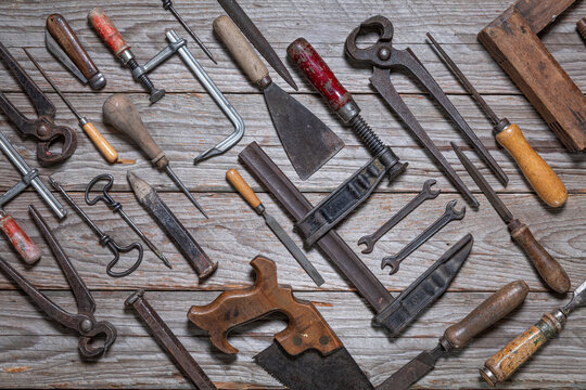 Top-down flat lay of vintage hand tools arranged diagonally on weathered wooden workbench
