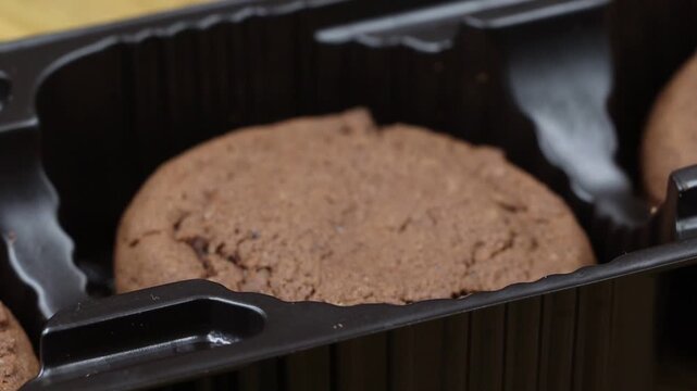 Close-up of a chocolate cookie in a packaging tray, rotating to showcase the baked treat.