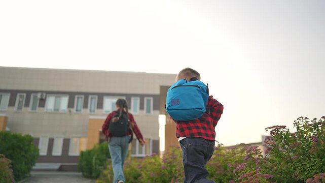Student boy walks fast on morning path chasing girl ahead. Sidewalk leads to school where siblings arrive daily. Walk to school brings motion and rhythm. Morning path filled with student energy