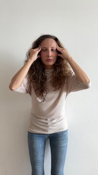 Mujer blanca con dolor de cabeza masajeando sienes