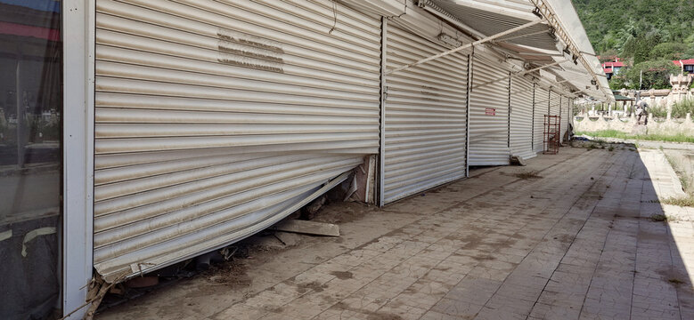Flood-damaged abandoned shops with collapsed metal shutters and debris in outdoor market, Elenite, Bulgaria