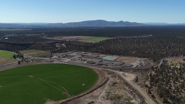 Aerial of construction and circular green farm field and hills in Redmond Oregon in spring