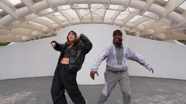 Two diverse young women dancing hip-hop in urban style on an outdoor stage