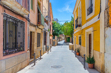 Obraz premium Alicante old town San Roque quarter, narrow street with typical houses, traditional colorful buildings, flowers and plants, Casco Antiguo Alicante city historical centre, Valencian Community, Spain