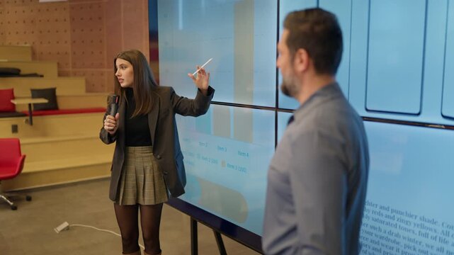 A businesswoman presents data and smartphone concepts to her attentive colleagues during a meeting. Employees actively engage in a collaborative modern workspace