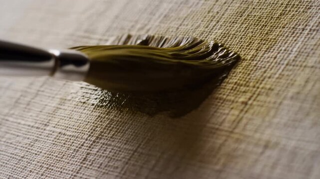 Paintbrush resting on textured beige surface