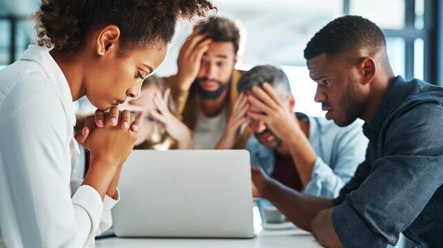 Stressed business team looking at a laptop with worried expressions, facing difficult challenges and potential failure in the office, discussing urgent deadlines