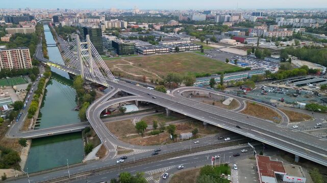 High angle twilight view of the modern Ciurel cable-stayed bridge in Bucharest, Romania. Scenic urban infrastructure with glowing traffic lights at sunset.