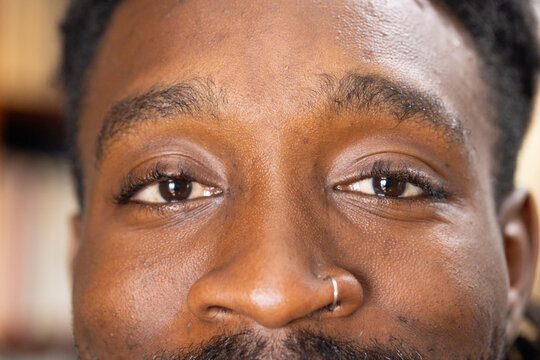 African American man gazing into camera in home study, showing silver hoop nose piercing