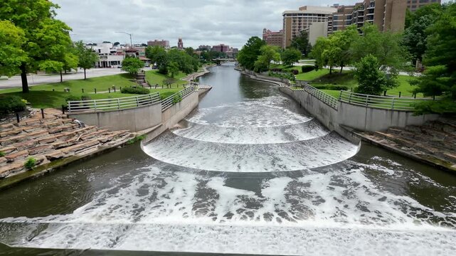 low drone flyover of small waterfall in city