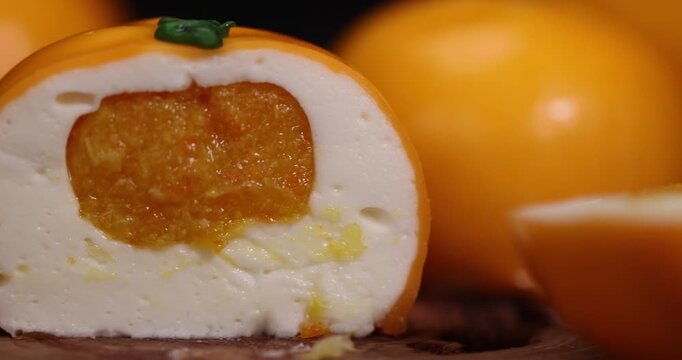 sweet calorie cake that simulates an orange is lying on the table, an orange sweet cake with orange flavor and orange pulp, good  food