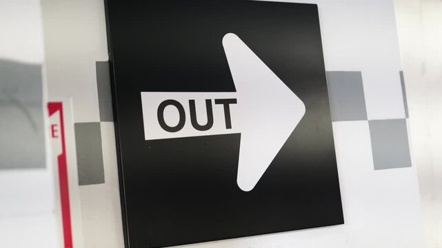 Black exit wayfinding sign with white arrow symbol
