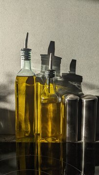 Glass oil dispenser cruet bottles in the morning sunlight with shadows. Olive and avocado oil.