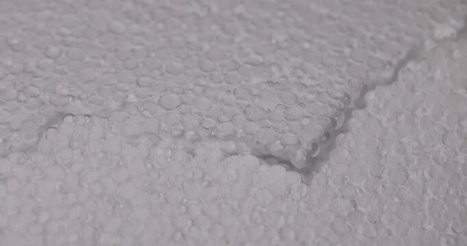 White foam with an uneven seam, this cellular foam consists of many small particles and is divided by a deep diagonal crease.