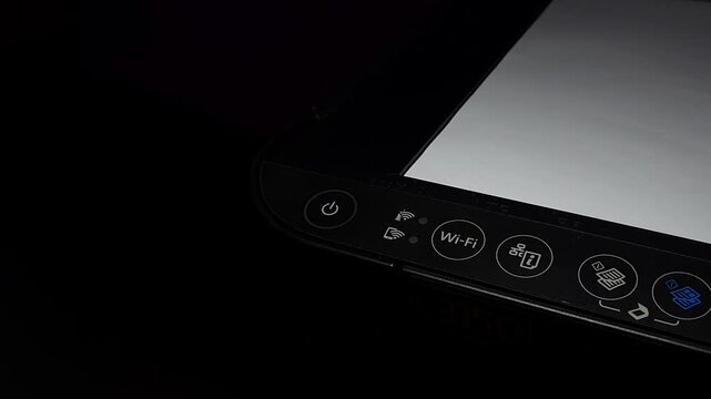 Pressing the wireless Wi-Fi connection button on a black multifunction printer panel.
