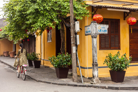 Woman riding a bicycle in the historic streets of Hoi An, Vietnam.