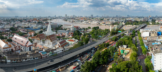 Fototapeta premium Bangkok, Thailand - A panoramic view of the Chao Phraya River and city skyline, featuring Wat Arun and a busy highway.