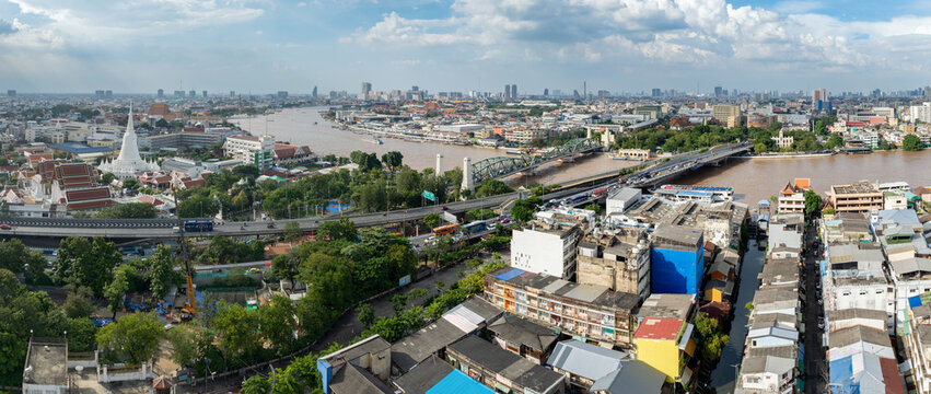 Bangkok, Thailand - A panoramic view of the Chao Phraya River and cityscape, featuring the Phra Sumen Fort and bridges, showcasing urban life and transportation.