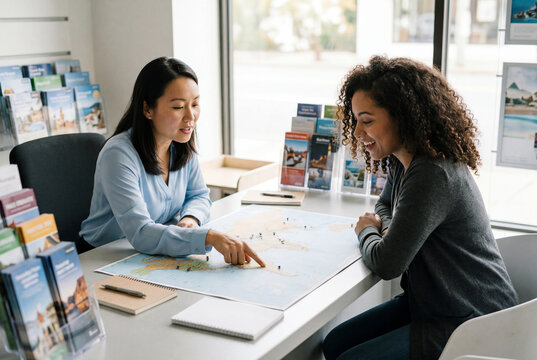 Travel agent pointing at world map discussing vacation with client