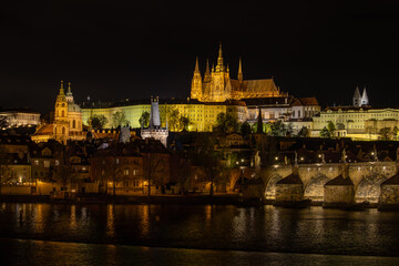 Fototapeta premium Panoramic night view of Prague Castle with St. Vitus Cathedral and Charles Bridge reflected on the Vltava River, Czech Republic
