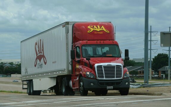 Irving, Texas, U.S.A - May 27, 2026 - SAIA LTL Freight semi-truck with red cab and white trailer traveling near residential area under cloudy sky.