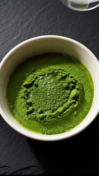 Preparing traditional Japanese matcha green tea by pouring hot water and whisking powder.