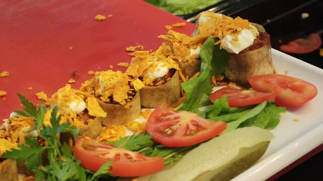 A detailed close up video of unique cig kofte sushi rolls topped with fresh yogurt, sweet pomegranate sauce, and crunchy corn chips, showcasing a creative Turkish fusion food presentation.