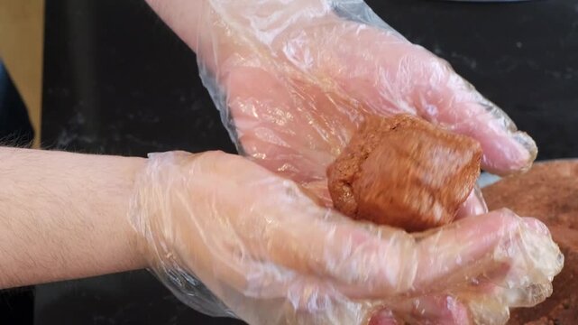 A close up video of a chef kneading a large batch of cig kofte, shaping a perfect piece by hand, and proudly showing it to the camera to display authentic Turkish street food craftsmanship.