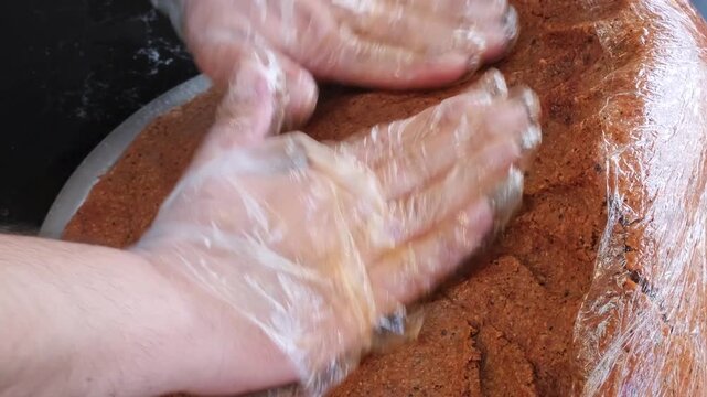 A detailed close up video of a master chef expertly kneading and massaging a large batch of traditional spicy cig kofte dough, showcasing the intense authentic Turkish culinary process.