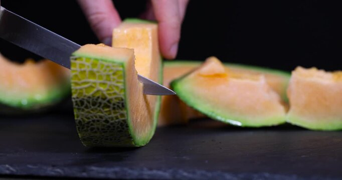 Melon fruit on a dark background, juicy tropical melon with delicate orange flesh and green edge on a stone slab with high macro detail and authentic organic texture.
