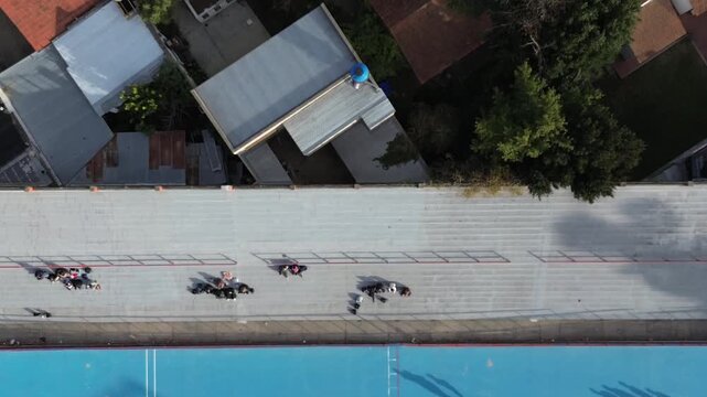 drone video of a city during the day, stadium and playground,
dramatic sky and sea horizon, aerial shot of a village by the ocean,