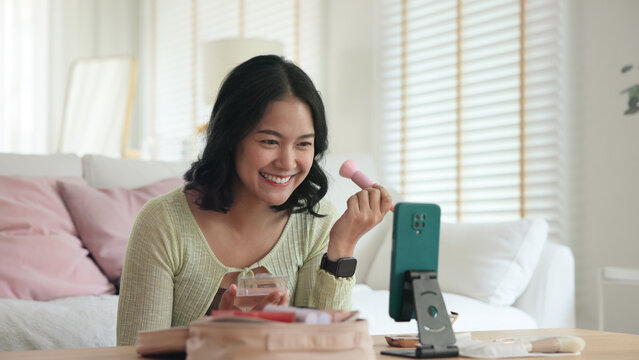 Asia people young gen z female happy smile enjoy phone apply selfie screen makeup blush virtual AI tech scan face app AR mixed augmented reality future beauty smart iot skin care help guide advice.