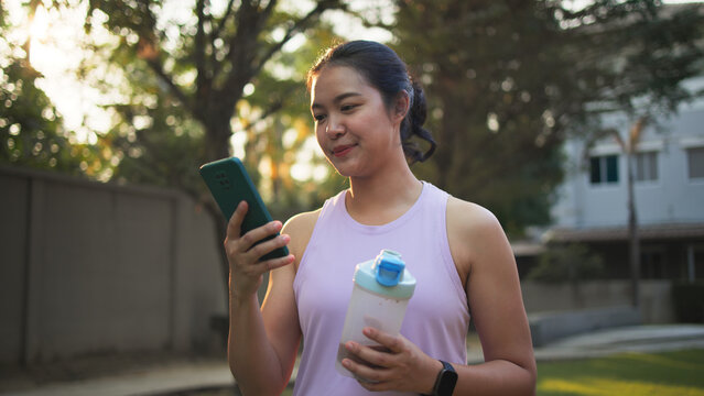 Young active woman drink whey protein shake bottle eating diet food using phone calorie AI plan app after workout health care asia people happy relax anti aging life weight loss public green park walk