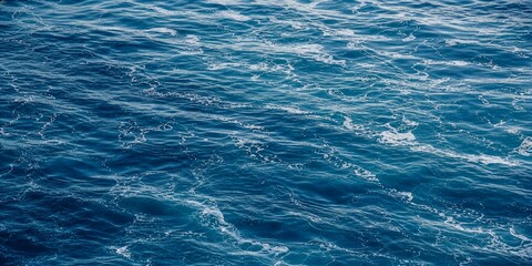 Obraz premium Deep Blue Ocean Water Surface Texture with Gentle Ripples, Flowing Waves, and White Sea Foam Creating a Calming Aquatic Background