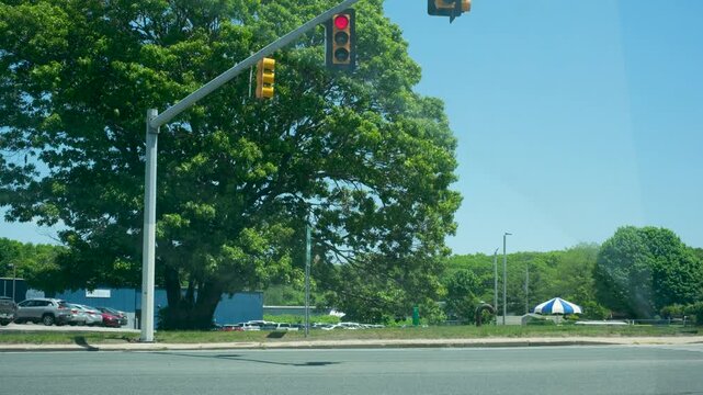 Street intersection traffic light with vehicles passing on road, sunny day b-roll