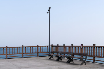Naklejka premium Wooden ocean observatory deck with empty benches and street lamp