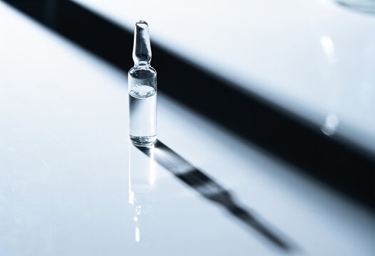 Glass ampoule on white background. Medical vial with clear liquid, injection vaccine, pharmaceutical solution, laboratory research concept, healthcare medicine, clinical science, pharmacy substance.