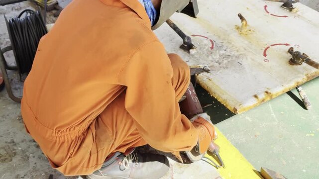 ship fitter cutting metal by electrical grinder, repair steel door. 