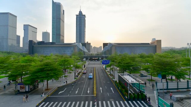 Modern city boulevard with skyscrapers and green trees at sunset