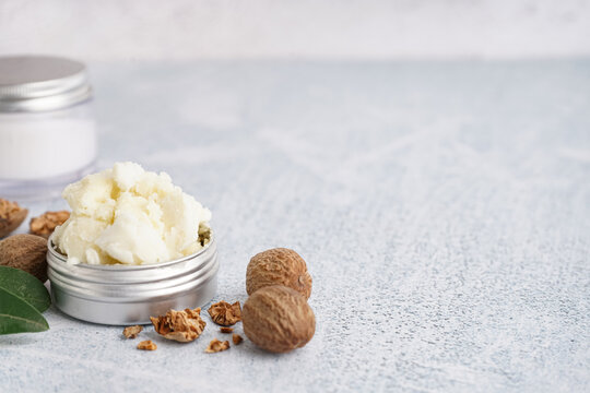 Jar of shea butter with nuts on grunge background, closeup