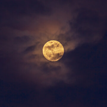 Super full moon in the night sky with clouds, natural background.