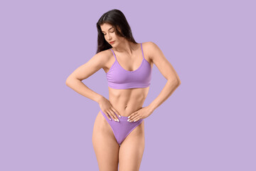 Fototapeta premium Pretty young woman in underwear on lilac background